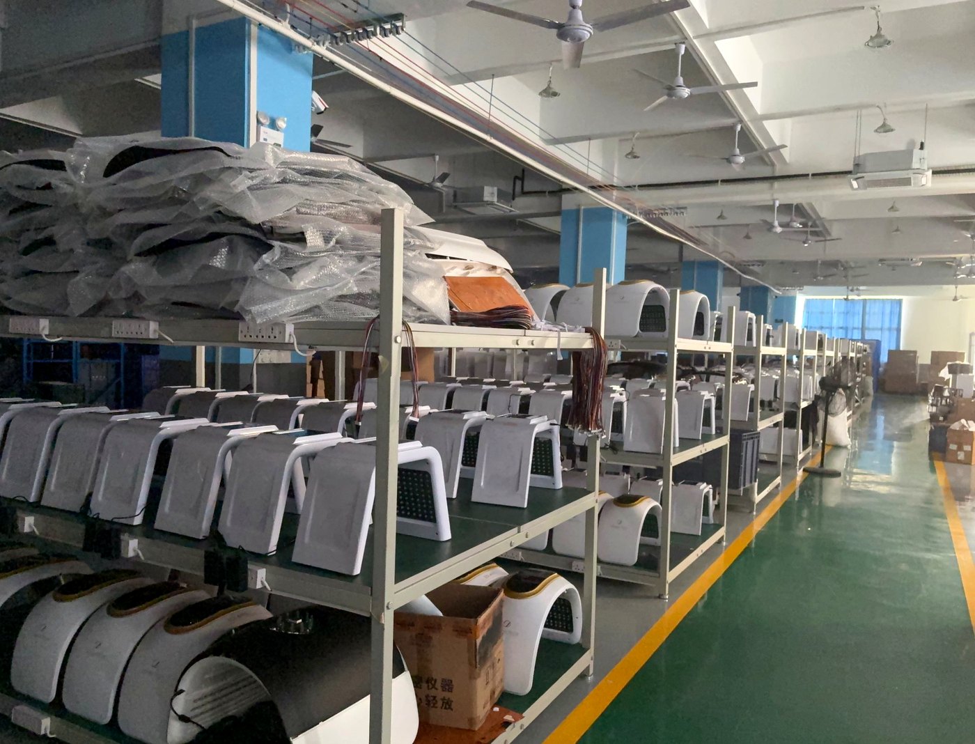 SaintQueen™ assembly line — gray device housings on production shelves