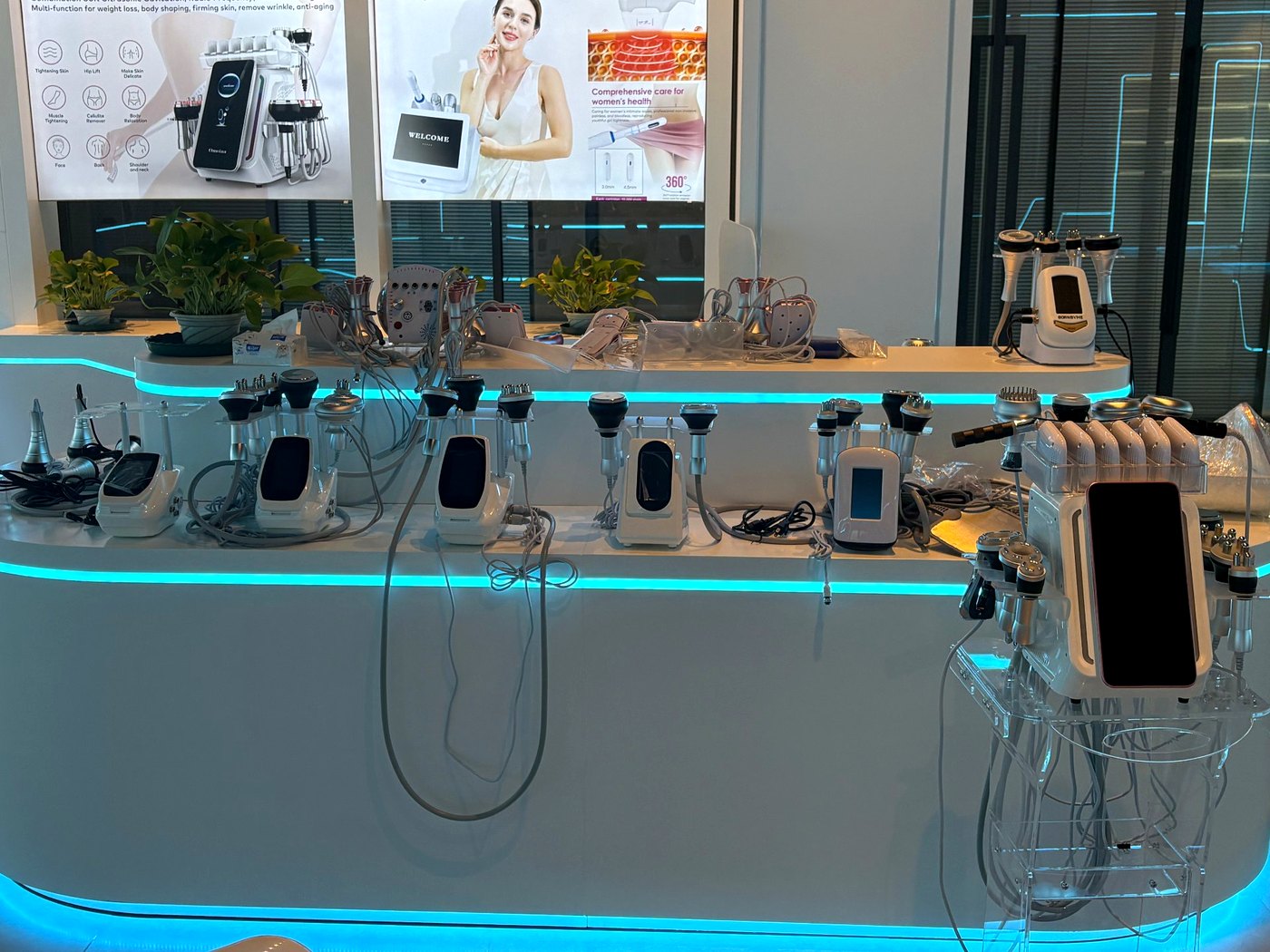 SaintQueen™ showroom — professional beauty devices on a curved LED-lit display counter